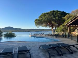 a deck with chairs and a swimming pool next to the water at Casa di Daisy - T2 les pieds dans l'eau et piscine in Pianottoli-Caldarello