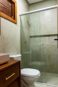 a bathroom with a toilet and a glass shower at Casa Revoada BG PI in Barra Grande