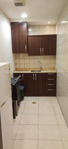 a kitchen with wooden cabinets and a sink and a refrigerator at عمارة النفيسة السكنية in Unayzah