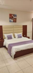 a bedroom with two beds with purple and white pillows at عمارة النفيسة السكنية in Unayzah
