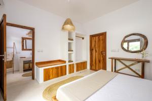 a bedroom with a white bed and a mirror at Coconut Villas Zanzibar in Matemwe
