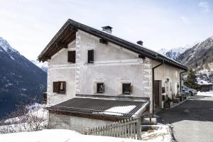 a building with snow on the ground next to a mountain at Chasa Sur Chafarrer in Guarda