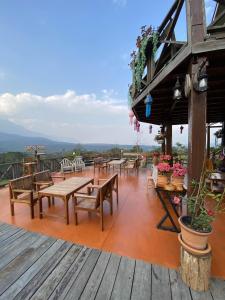 a restaurant with tables and benches on a deck at มาดูดอย - Madoodoi in Ban Mae Na