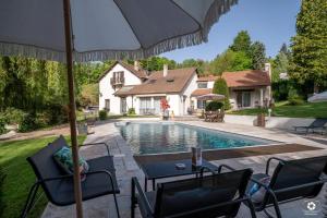 a swimming pool with chairs and an umbrella next to a house at La Petite Vernoelle in Prémilhat +12 photos