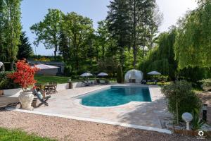 a swimming pool in a yard with a patio and trees at La Petite Vernoelle in Prémilhat