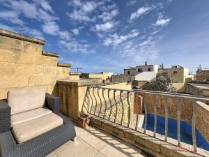 a chair sitting on top of a balcony at Mia - Your Gozo Haven with Pool in Xagħra
