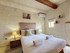 a bedroom with a large white bed with towels on it at Mia - Your Gozo Haven with Pool in Xagħra +41 photos
