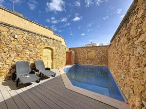 a patio with two chairs and a swimming pool at Mia - Your Gozo Haven with Pool in Xagħra