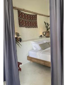 a bedroom with a white bed with a curtain at Triggerfish Hut at Casa Domingo in Ban Thong Phlu