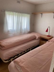 two beds in a room with a window at Houseboatvinkeveen Lelie in Vinkeveen