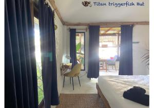 a bedroom with blue curtains and a bed and a table at Triggerfish Hut at Casa Domingo in Ban Thong Phlu