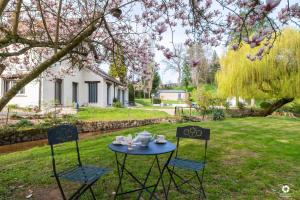 a table and two chairs in a yard with pink flowers at La Petite Vernoelle in Prémilhat