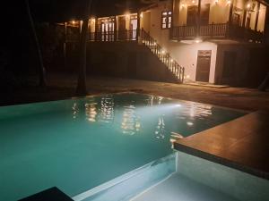 a swimming pool at night with a house in the background at Cinnamon Lagoon Villas in Unawatuna