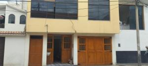 a building with two wooden doors and windows at Departamento Huanchaco in Huanchaco