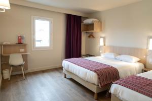 a hotel room with two beds and a window at Hotel Espace Cite in Carcassonne
