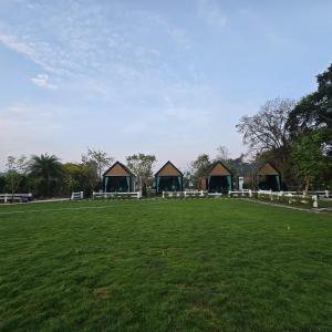 a large grass field with buildings in the background at ลึกลับรีสอร์ทบ้านนา in Nakhon Nayok