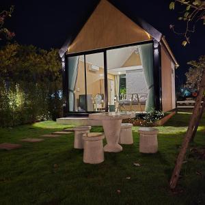 a house with a table and benches in the grass at ลึกลับรีสอร์ทบ้านนา in Nakhon Nayok