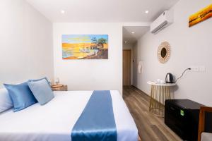 a bedroom with a bed and a painting on the wall at Cybade Hôtel in Phú Quốc +37 photos