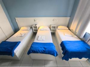 two beds in a small room with blue and white at Hotel Portugal in Macaé +5 photos
