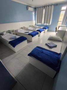 four beds in a room with blue walls at Hotel Portugal in Macaé