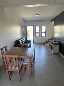 a living room with a table and a couch at Casa geminada a 250 metros do mar in Imbituba +4 photos