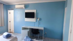 a blue room with a desk and a chair at Hotel Portugal in Macaé