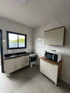 a small kitchen with a sink and a microwave at Casa geminada a 250 metros do mar in Imbituba