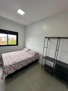a bedroom with a bed and a shelf in it at Casa geminada a 250 metros do mar in Imbituba
