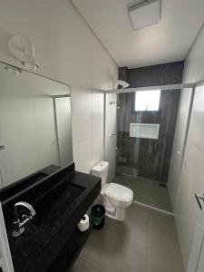 a bathroom with a sink and a toilet and a mirror at Casa geminada a 250 metros do mar in Imbituba