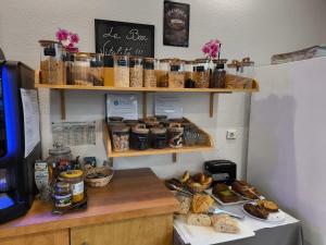 a counter with bread and other food items on shelves at Hôtel Le Laury's-hôtel calme proche de Rodez avec parking privé gratuit-Arrivée après 20h possible via borne automatique in Onet le Château