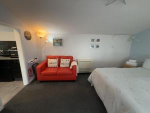 a bedroom with a red chair and a bed at The Garden Suite Holt in Holt