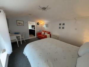 a bedroom with a white bed and a red couch at The Garden Suite Holt in Holt