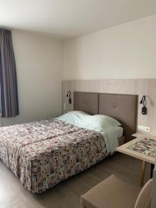 a bedroom with a bed and a table at Hotel Cleo in Kasterlee
