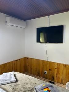 a bedroom with a flat screen tv on the wall at Eco Chalés Águas Claras in Lumiar