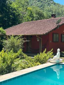 a house with a pool and a statue next to a house at Eco Chalés Águas Claras in Lumiar