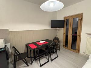 a room with a table with chairs and a television at Cozy Mountain Apartment with Cimone view in Faidello