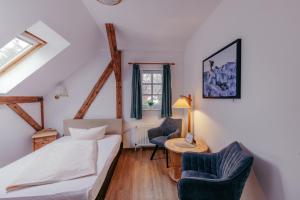 a bedroom with a bed and two chairs at Hotel Schlösschen Sundische Wiese Zingst in Zingst