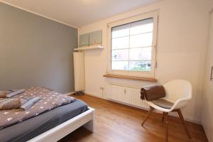 a bedroom with a bed and a chair and a window at MeerGlück in Langeoog