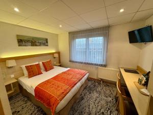 a hotel room with a bed and a desk at Logis Hôtel Restaurant & Spa au Soleil in Wettolsheim