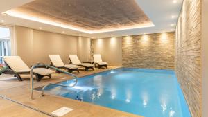a pool in a hotel room with chairs and a poolificialificialificialificialificial at Logis Hôtel Restaurant & Spa au Soleil in Wettolsheim