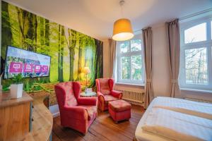 a bedroom with a bed and two red chairs at Hotel Schlösschen Sundische Wiese Zingst in Zingst
