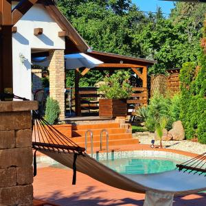 a hammock in a backyard with a pool at Relax Holiday House in Balatonrendes