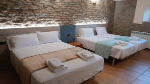 a room with two beds and a stone wall at Cal Fortic, Navès in Navés +41 photos
