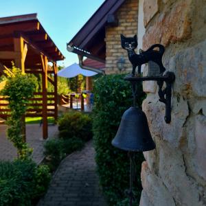 a black cat on a bell on a stone wall at Relax Holiday House in Balatonrendes