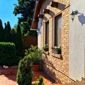 a brick house with potted plants and a window at Relax Holiday House in Balatonrendes