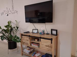 a flat screen tv on a wall with a wooden table at Au P’Tit Cosy in Bazincourt-sur-Saulx