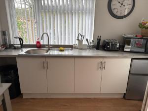 a kitchen counter with a sink and a clock on the wall at Pinecroft in Pembrokeshire