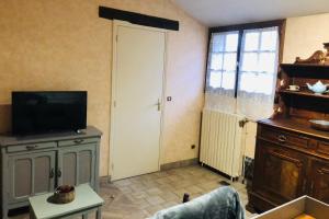 a living room with a flat screen tv and a door at La Renardie in La Ferté-Imbault