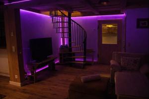 a purple room with a staircase and a tv at Chalet Steiermark in Pusterwald