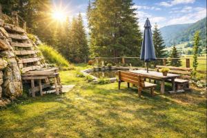 an umbrella and a bench and a table with an umbrella at Chalet Steiermark in Pusterwald +7 photos